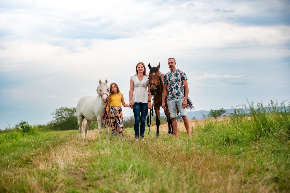 Homme, femme et jeune fille avec deux chevaux dans la nature